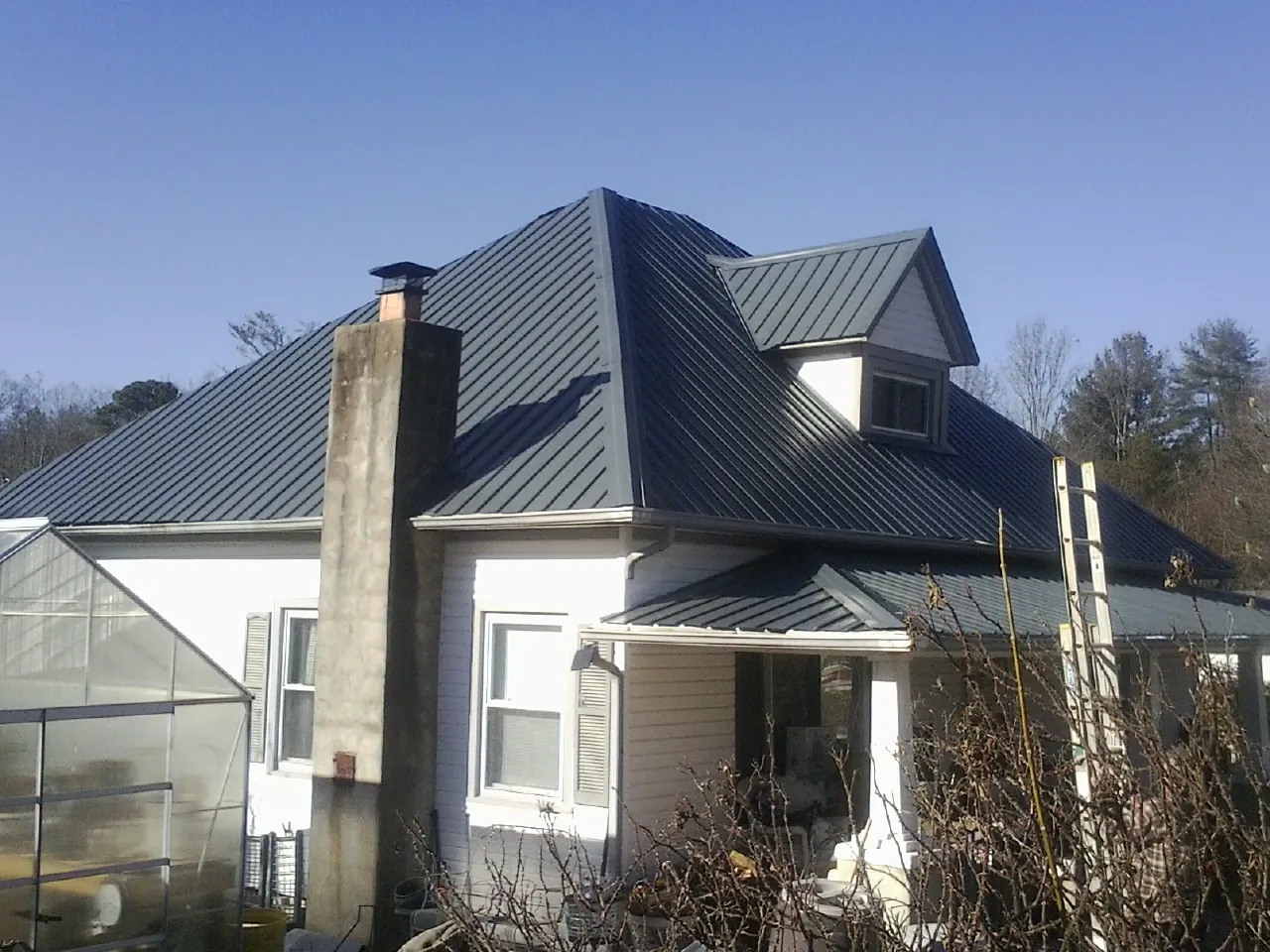 Dark blue standing seam metal roof on a white farmhouse with dormer — Slate & Tile Roof Repair by Roofing Brothers in Pike