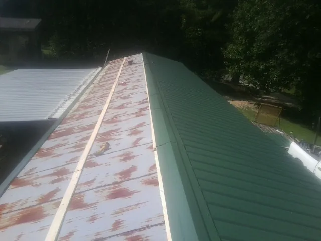 Old rusted panels beside newly installed green metal roofing — Wind Damage Roof Repair by Roofing Brothers in Pike