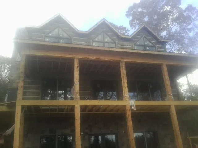 Dormers and porch framing on a large log home under construction — Roof Coating work by our crew in Pike