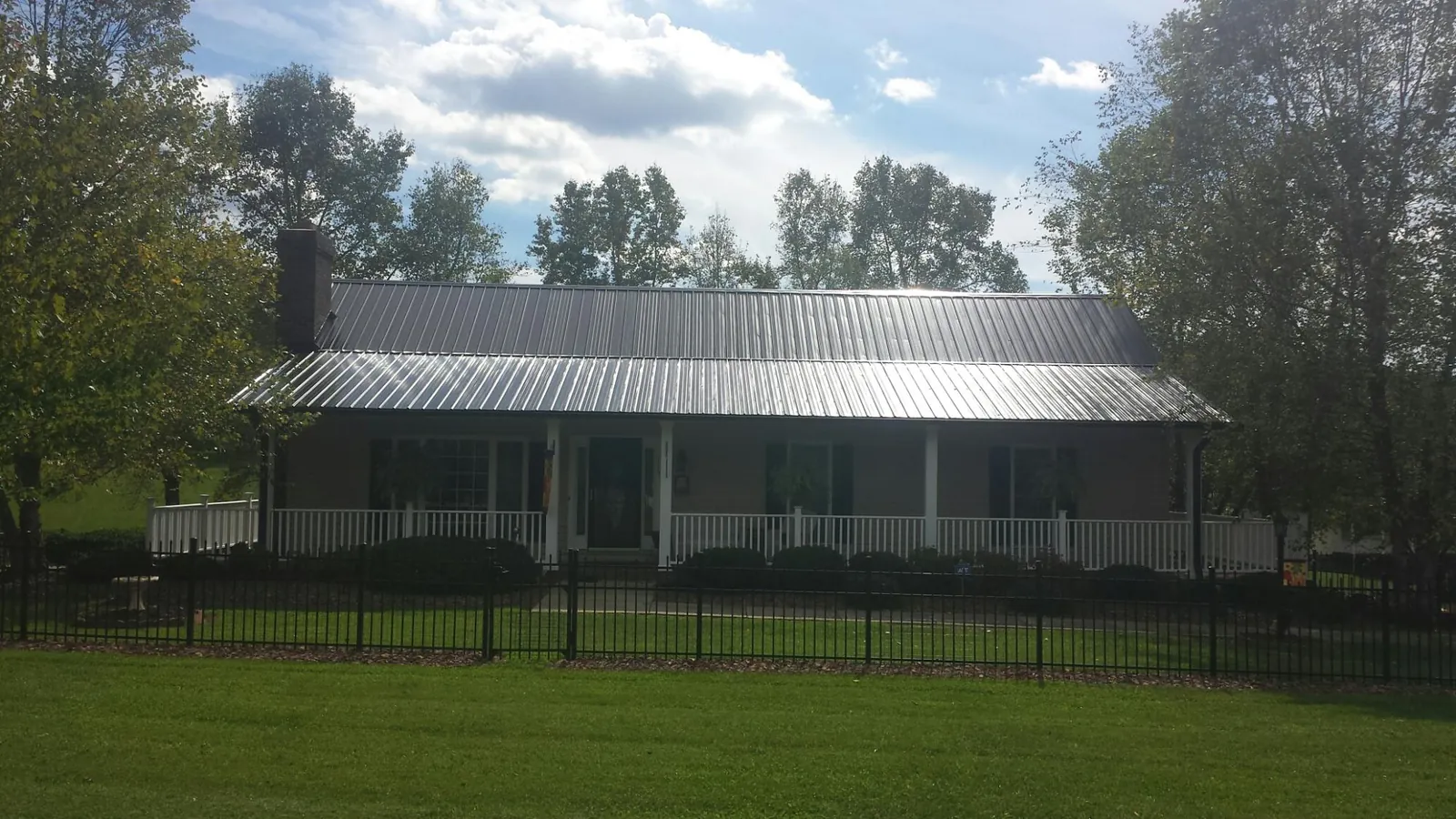 Gray metal roof on a brick ranch with a full width front porch — Gutter Guard Installation work by our crew in Pike