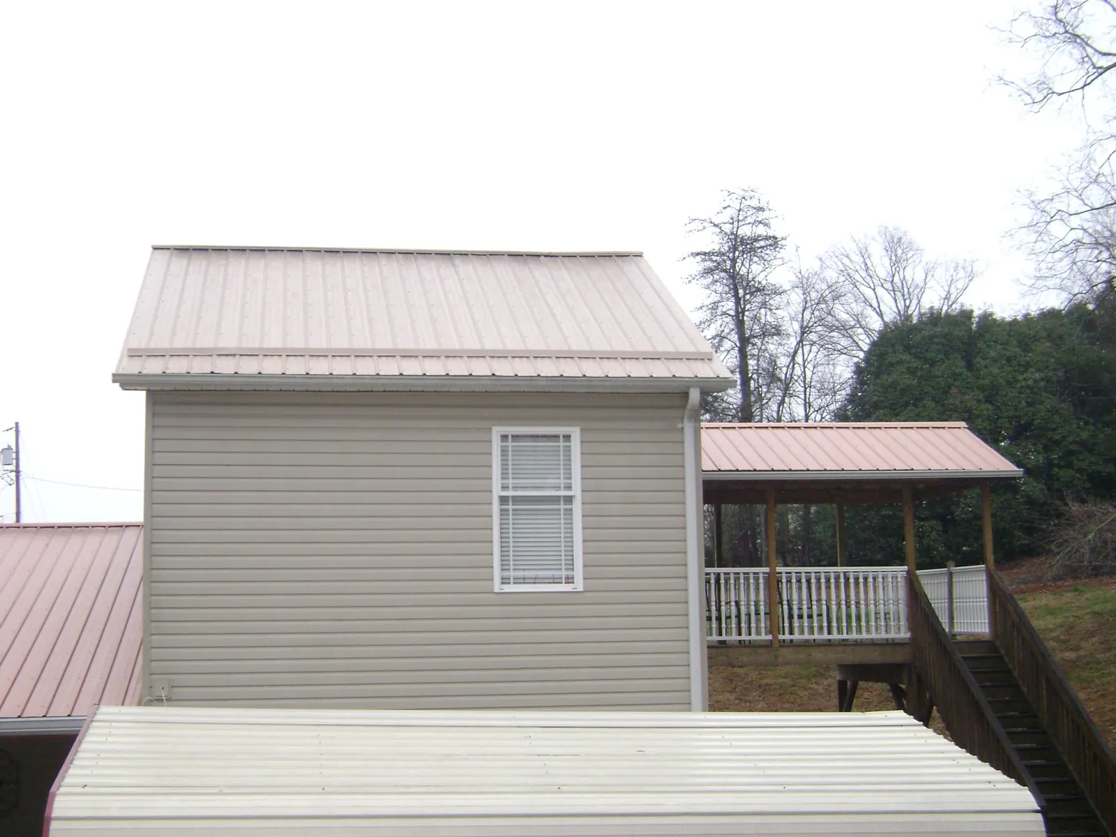 Tan metal roofs on a two story addition and attached porch, from a Roof Replacement job in Pike