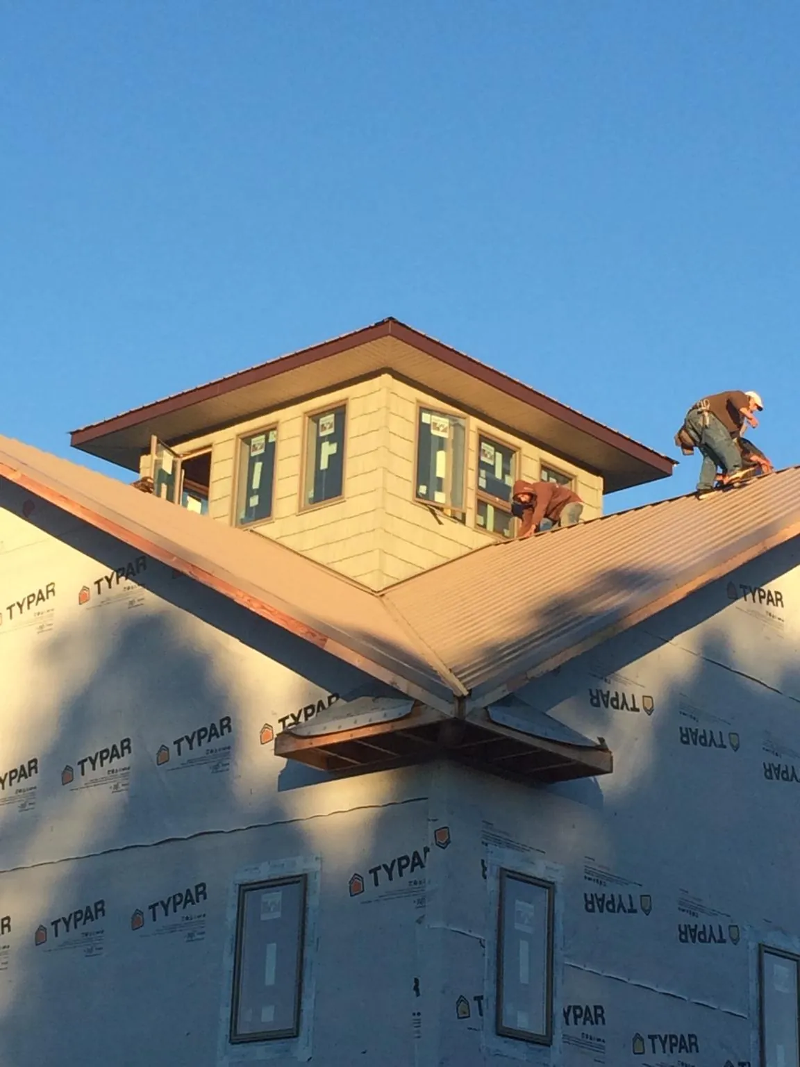 Roofers working around a rooftop cupola on a new metal roof at sunset — Roof Waterproofing in Pike by Roofing Brothers